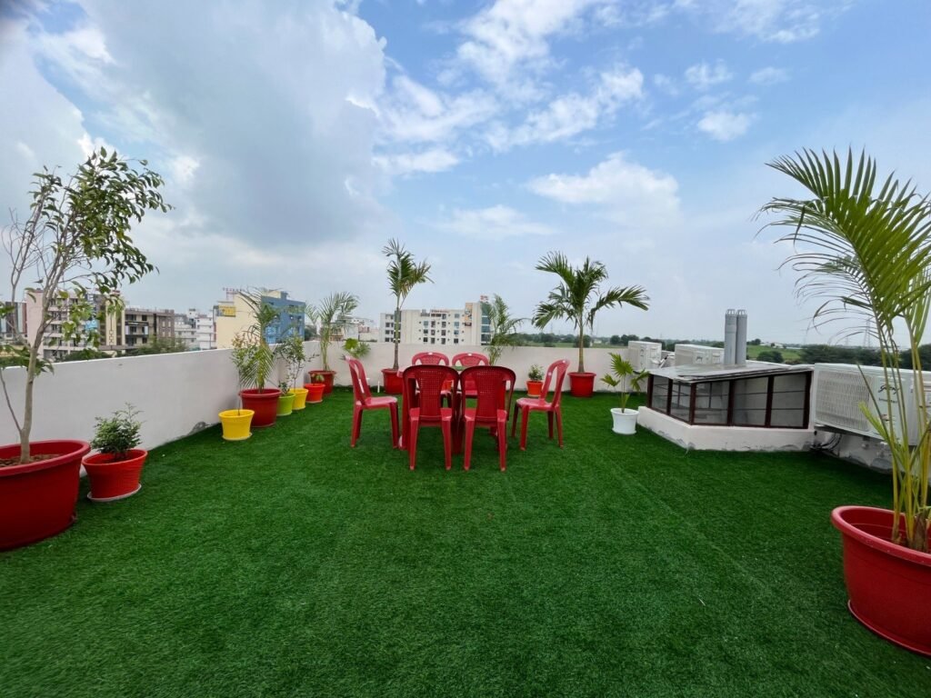 rooftop-cafeteria-terrace-garden-girls-pg-jaipur Rooftop terrace garden with grass flooring and cafeteria area at The Cosmos Girls Hostel, Dahmi Kalan.